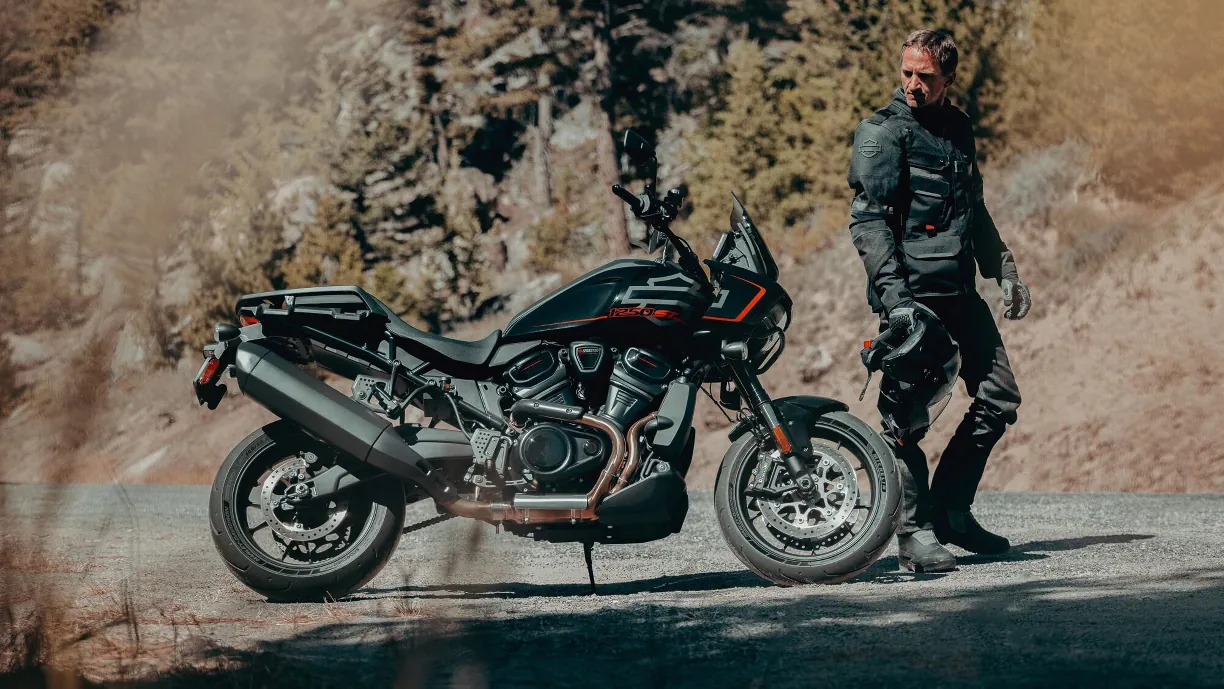 Harley-Davidson Pan America 1250 ST negra aparcada al costat del seu pilot, amb el casc a la mà